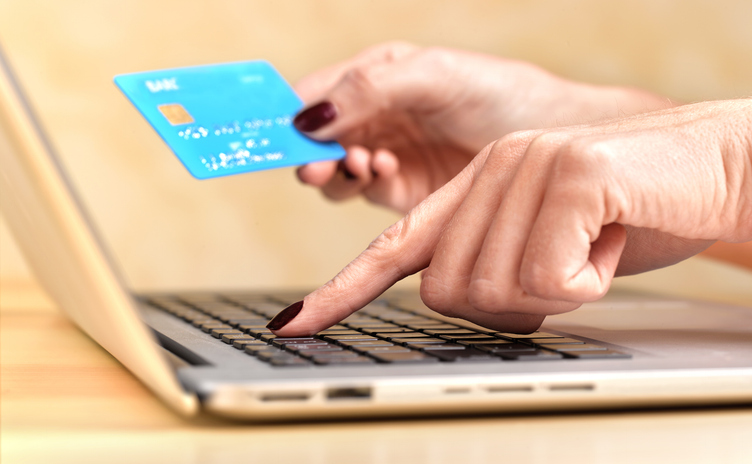 Close up of a woman at her laptop using a credit card to completer and online purchase
