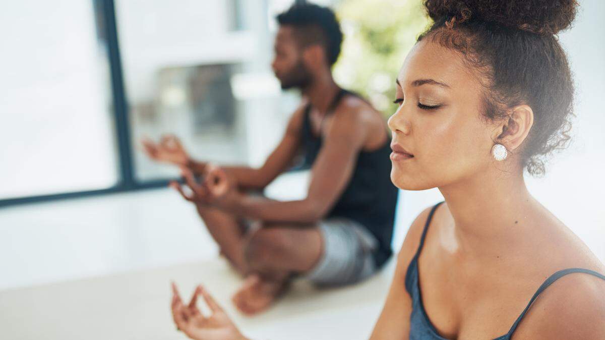 Shot of two people doing yoga together in a studio