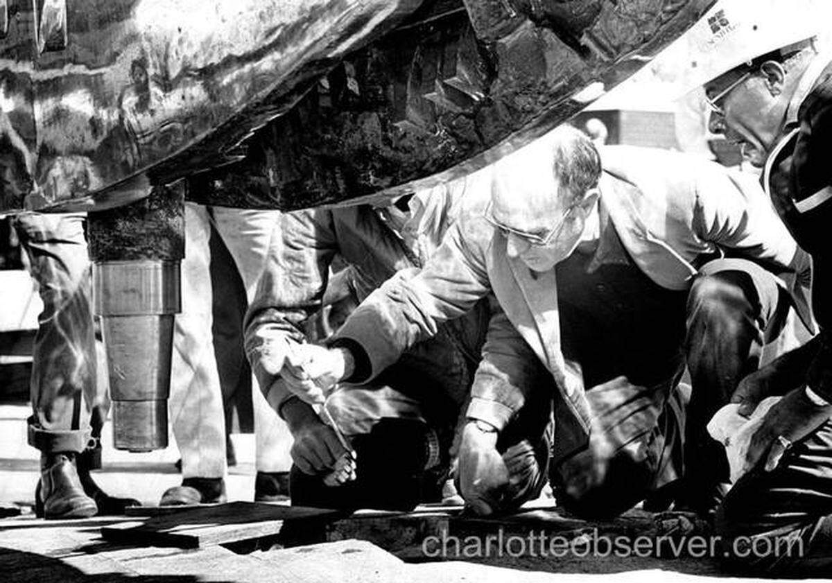 Artist Arnaldo Pomodoro inspects his sculpture.