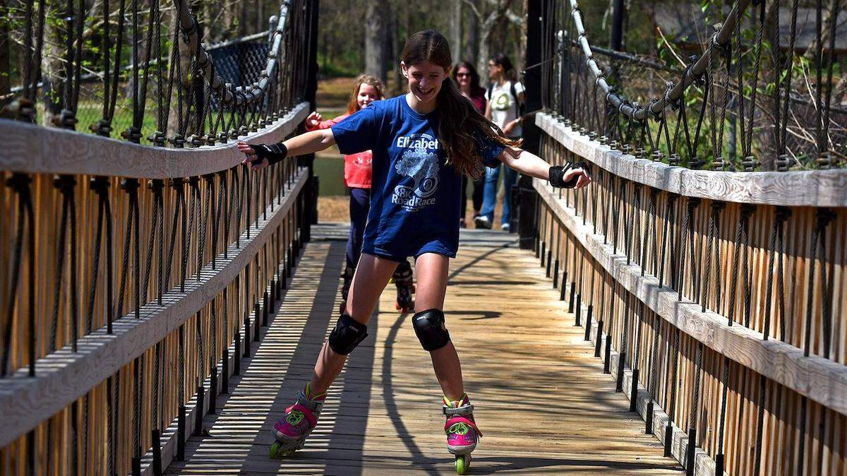 Abbie Driscoll, 10 yrs., leads friend Geneva Everhart, 10 yrs., across a bridge over the Little Sugar Creek on rollerblades at Freedom Park on Monday, March 27, 2017.