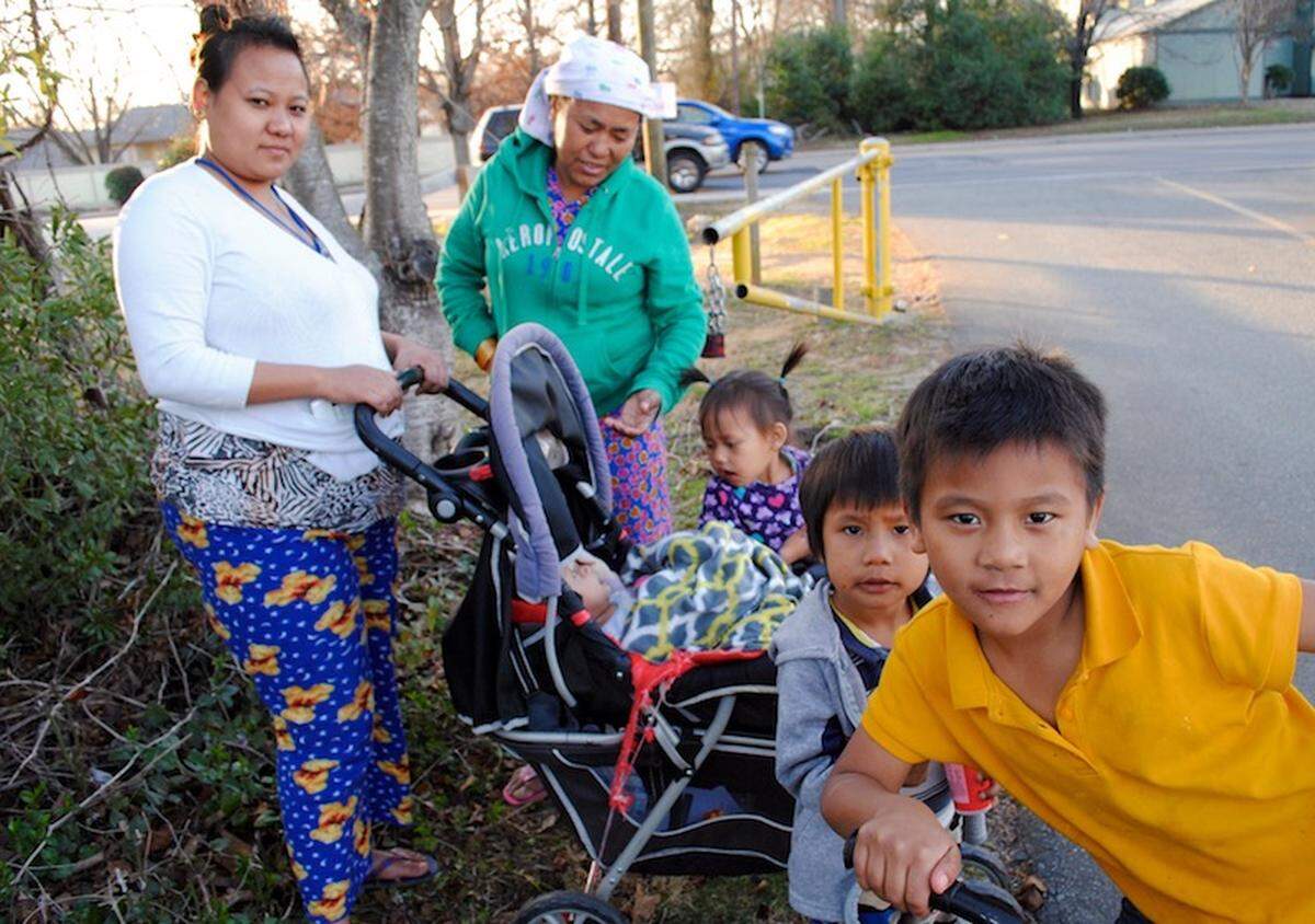 Sancha Lama Tameung (left), 27, walks home from a trip to Compare Foods. She is pictured here with her mother and four children.