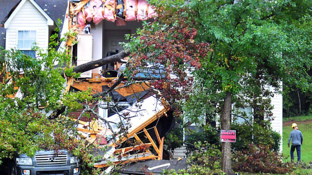 A utility worker examines the damage to a home on Long Grass Ct. in northwest Charlotte Saturday, Oct. 3, 2015. A toppled tree ripped through the front the house as winds and rain crossed the region.