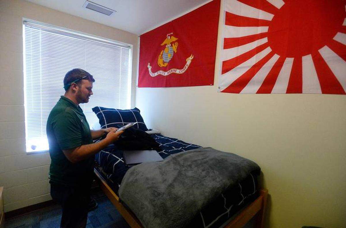 Photo by David T. Foster III/The Charlotte Observer<br>Ricky Beekman, whose online alter ego is known as Richard Joseph, is seen in his UNC Charlotte dorm room, decorated with a Marine Corps flag and a Japanese naval flag.