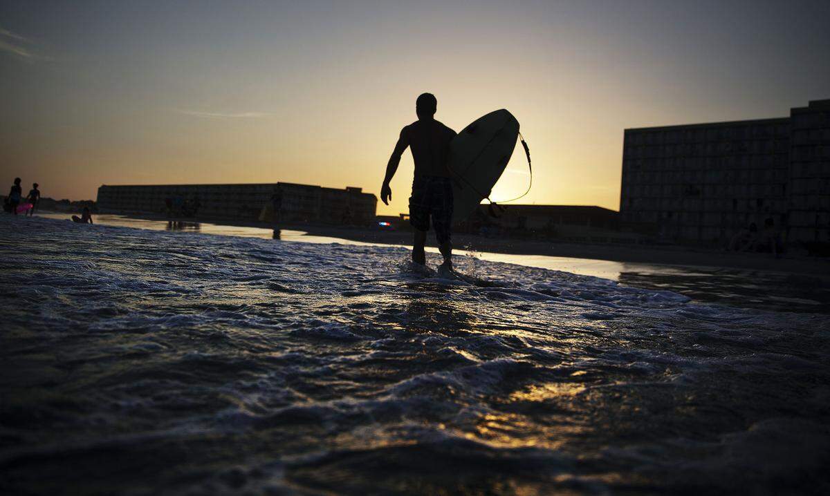 Chad Riner, of Folly Beach, S.C., walks out of the ocean after surfing as the sun sets, Tuesday, June 16, 2015, in Folly Beach. The region is seeing temperatures around the 100 degree mark which is expected to continue through Thursday. (AP Photo/David Goldman)