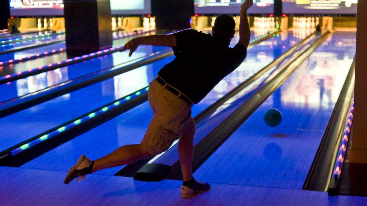 Erik Combs releases his ball at the foul line. He and co-workers from Wild Wing in EpiCentre were bowling and eating after work on a recent afternoon. Strike City, a new combination bowling alley-bar-restaurant-hangout is opening in EpiCentre. From the blacklights to the pumping music to the day-glo balls to a couple dozen beers on tap, this is definitely not your father's bowlling alley.
GARY O'BRIEN - gobrien@charlotteobserver.com