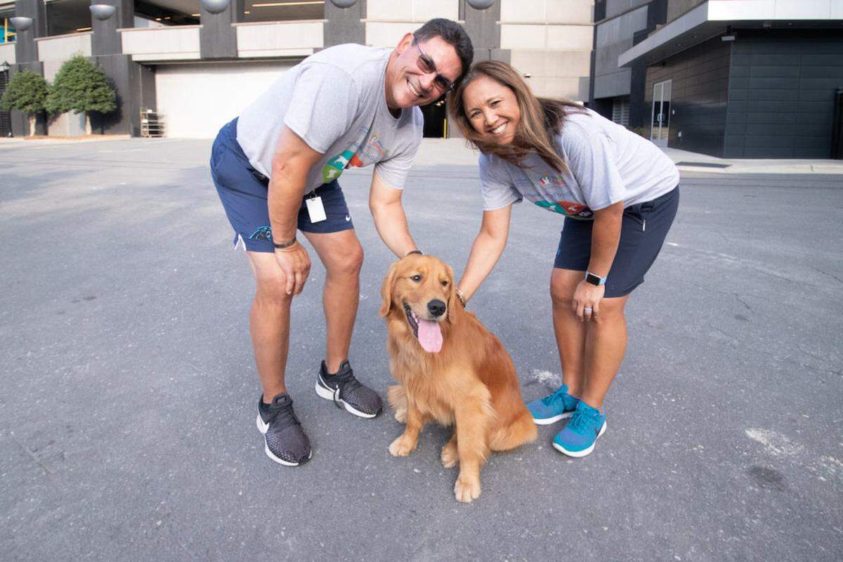 Alex Cason Photography<br/>Ron and Stephanie Rivera with their golden retriever, Tahoe, at Bank of America Stadium in September 2019.