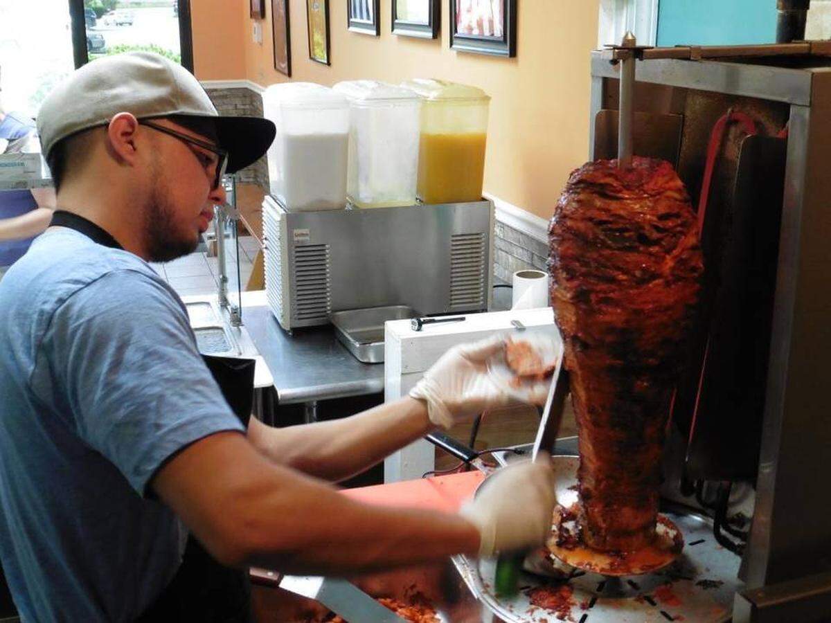 Alberto Turuda slices pork from the trompo spit at Tacos El Regio.