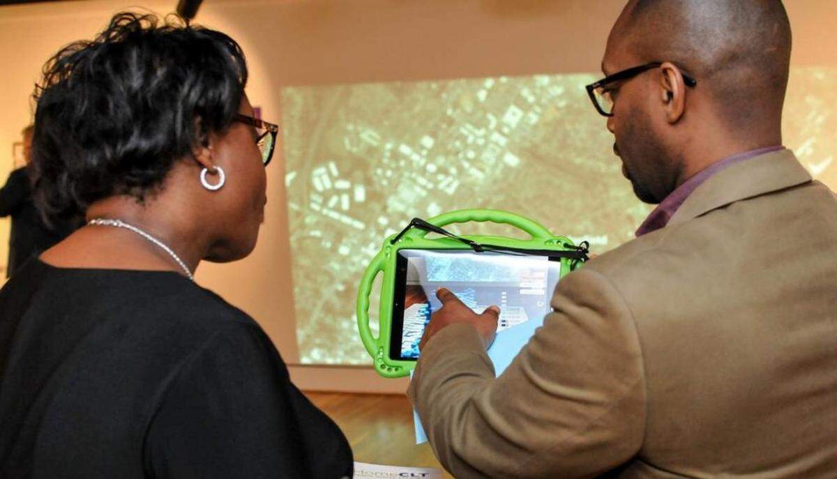 Courtesy of Lady Latimore Photography<br>Levine Museum historian Willie Griffin (right) explains the augmented reality piece of the #HomeCLT exhibit to a museum patron.