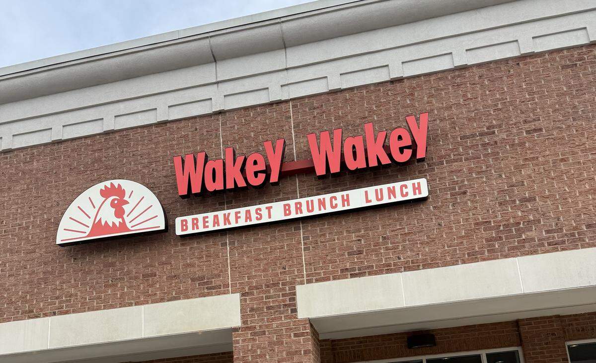 A photo of the exterior of a new restaurant called “Brunchtime,” located in a brick building in a strip mall. The restaurant’s name is displayed in large red letters above the entrance, with a small sign below reading “coming soon” and confirming the offering of “BREAKFAST - BRUNCH - LUNCH.”
