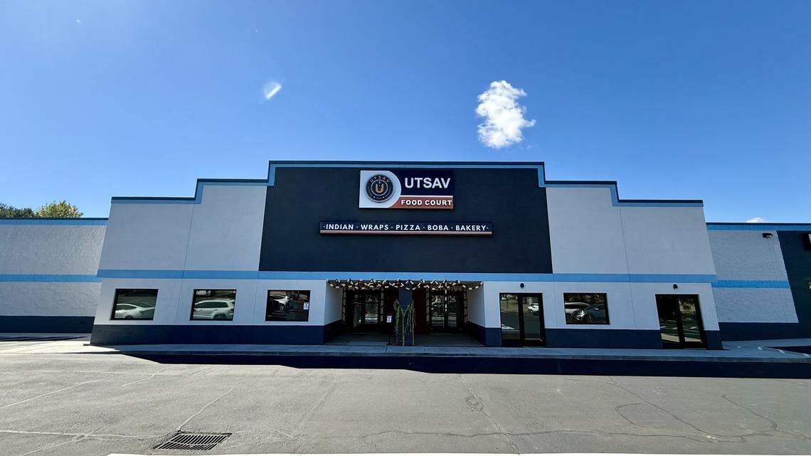 A single-story building with a gray and light blue facade houses the Utsav Food Court. The sign above the entrance advertises a variety of food options, including Indian, Wraps, Pizza, Boba, and Bakery.