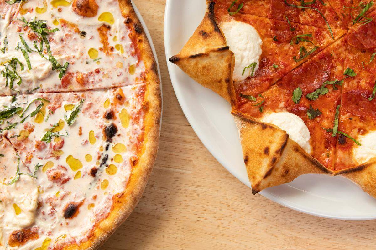 An overhead shot displays a round white pizza with basil and a star-shaped pepperoni pizza with ricotta-filled crust points.