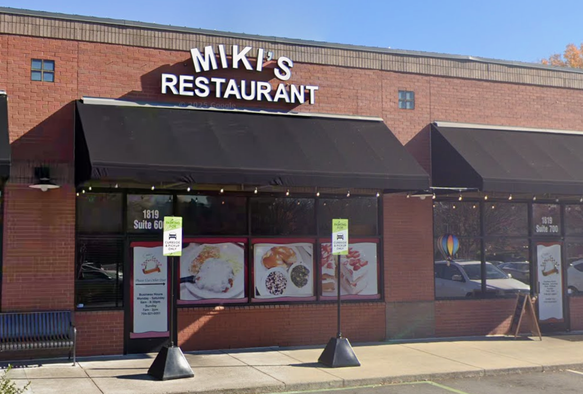 The exterior of Miki’s Restaurant is shown, featuring a red brick facade with black awnings and large window displays of breakfast and brunch dishes. The storefront includes designated curbside pickup signs and the street address “1819 Suite 600” visible on the glass door.