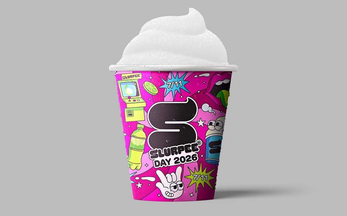 This promotional image showcases a 7-Eleven Slurpee cup topped with a high peak of white, icy slush. The cup is wrapped in an energetic, bright pink graphic design packed with eclectic cartoon elements like open mouths, lime slices, and speech bubbles. The central design elements include a bold, black “S” icon alongside the text “SLURPEE DAY 2026” to celebrate the annual event.