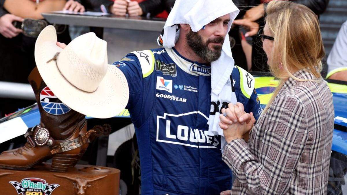 Jimmie Johnson wears a towel over his head as he cools off while talking with his wife Chandra in victory lane after winning the NASCAR Cup Series auto race at Texas Motor Speedway in Fort Worth, Texas, Sunday, April 9, 2017. (AP Photo/Larry Papke)
