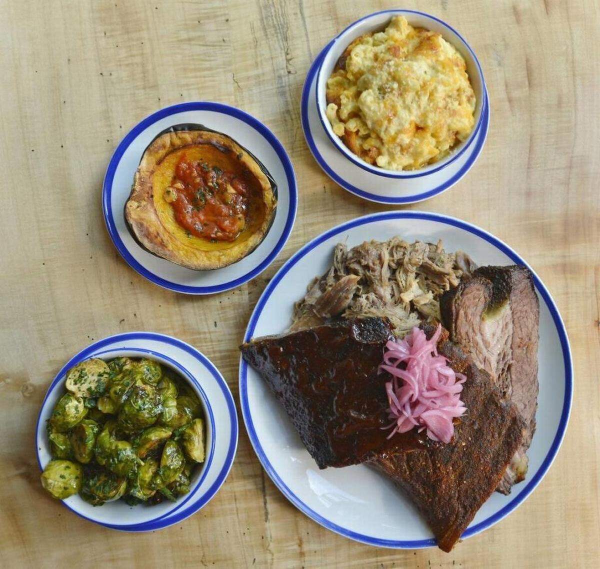 The Cue Combo tray at City Smoke: Brisket, pulled pork, Kansas City and Texas ribs, with sides of rotisserie Brussels sprouts, roasted acorn squash and mac &amp; cheese.