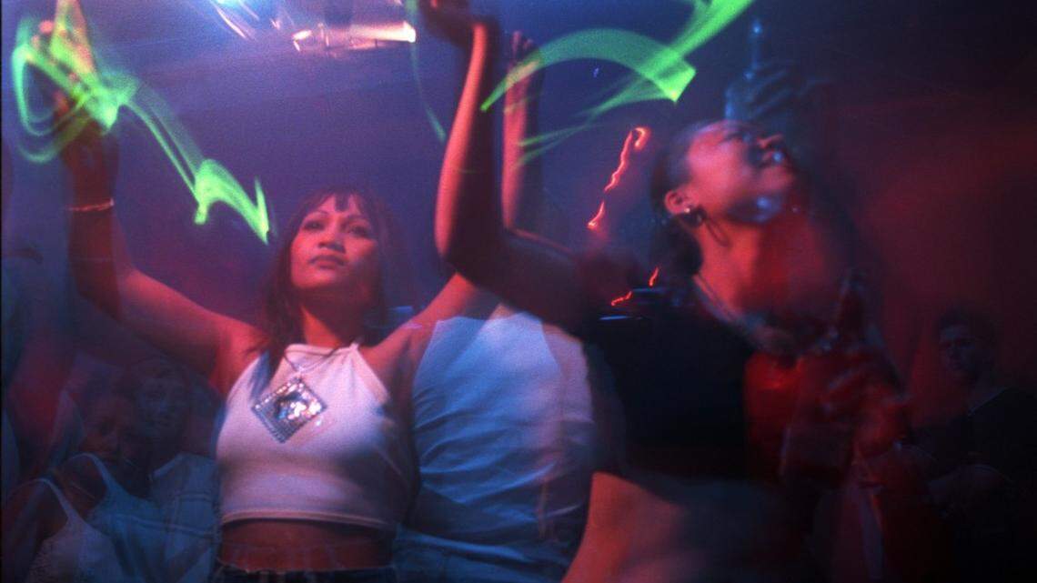 Khio Senensom (left) dances with a glow stick with her friend Lil Lee late night as DJ Andy K spins his house music at Mythos dance club on August 24, 1999.