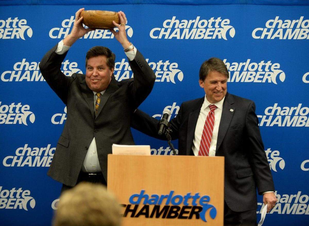 John McCabe, left, senior vice-president of Global Operations at PayPal, holds up a carved wooden bowl presented to him by Gov. Pat McCrory, right,  after McCrory announced that PayPal, Inc. will open a Global Operations Center in Charlotte.