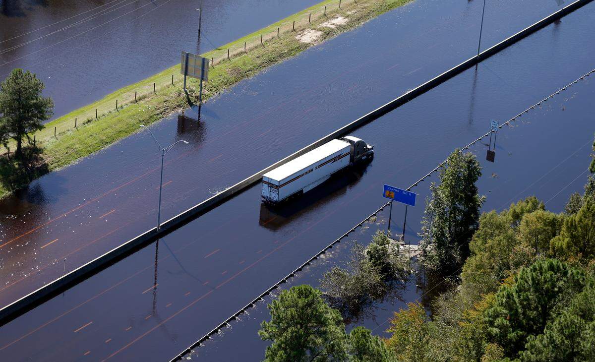 An abandoned tractor trailer on I-95 is surrounded by floodwaters from Hurricane Matthew in Lumberton, N.C., Wednesday, Oct. 12, 2016. People were ordered to evacuate, and officials warned that some communities could be cut off by washed out roads or bridge closures. (AP Photo/Chuck Burton)