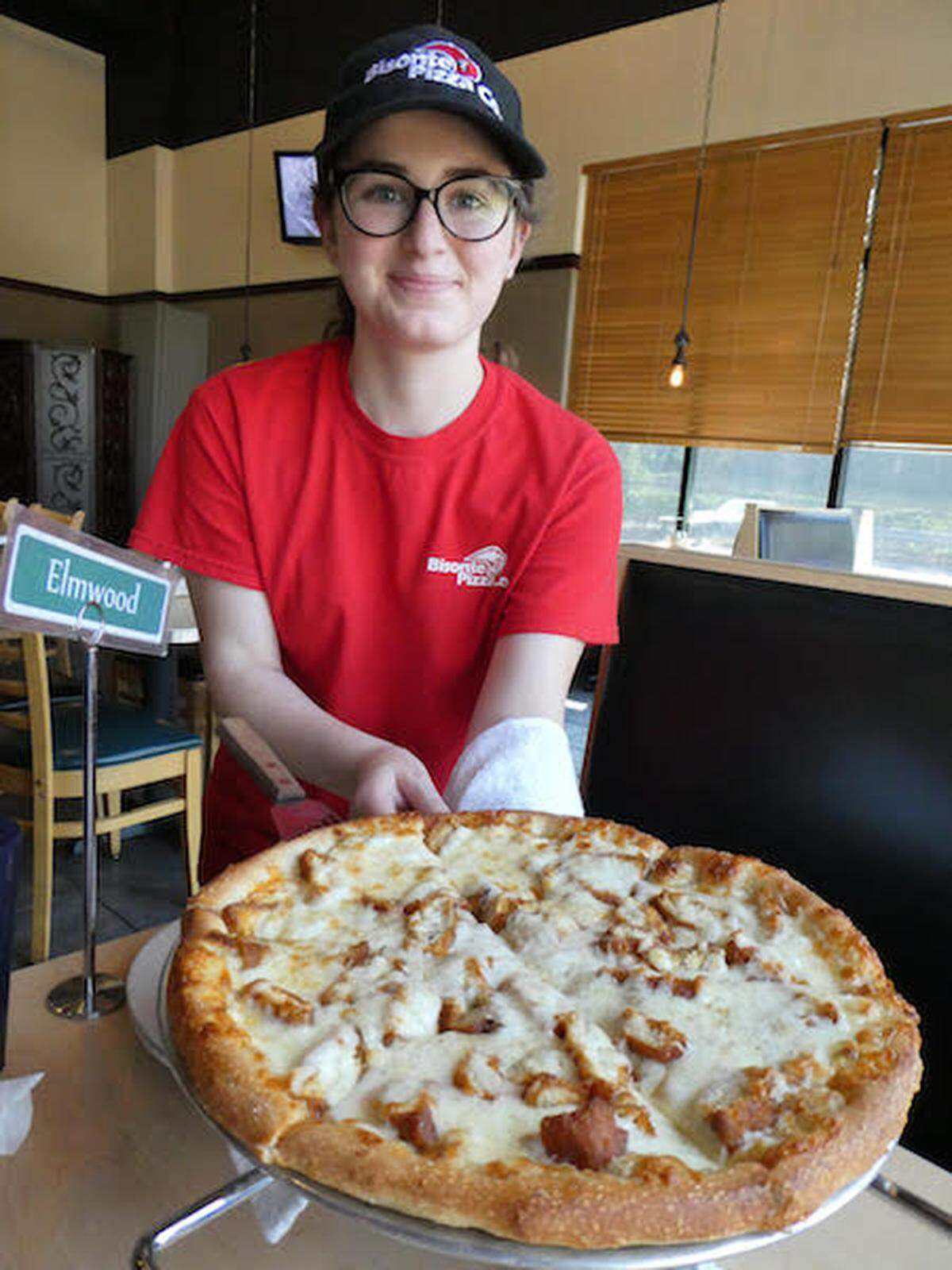 Bisonte server Sabrina Carmichael delivers a Buffalo chicken pizza with the signature Buffalo-style doughy crust. Photo by Tom Hanchett
