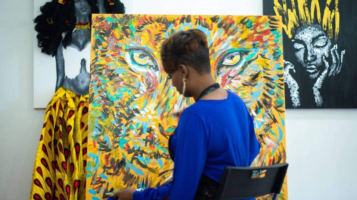 Photo by Joshua Komer<br>Whitney Austin works on a painting of a lion in her studio. She has quickly gained tens of thousands of followers on social media and is opening her third studio, this time at Carolina Place Mall.