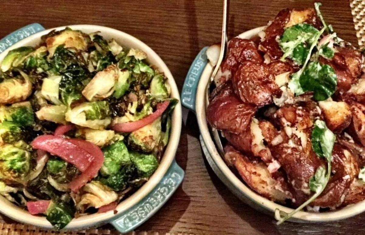 Oak Steakhouse’s sides are special: The sweet/tart charred Brussels sprouts (left) and the creamy/garlicky smashed potatoes with truffle aioli.Photo by Kathleen Purvis