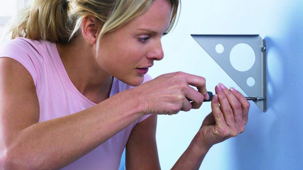 Woman Attaching a Bracket to a Wall with a Screwdriver