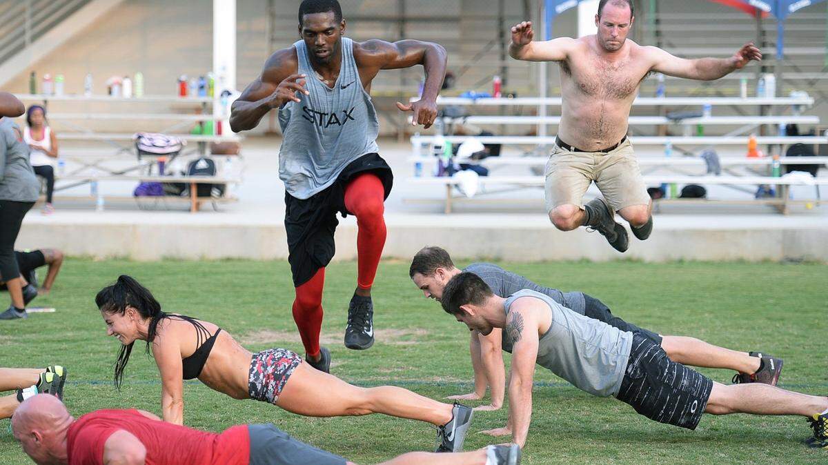 Former NFL star Randy Moss, left,  leaps over fellow participants in one of the bootcamp exercises, a leapfrog exercise, during the free twice-a-week boot camp being co-led by Moss, who now lives in Charlotte, and 2X Crossfit games athlete Emily Breeze. Breeze and Moss came up with the idea as a way to give back to the community they both love so much. Hundreds participated in this session on September 2, 2015.