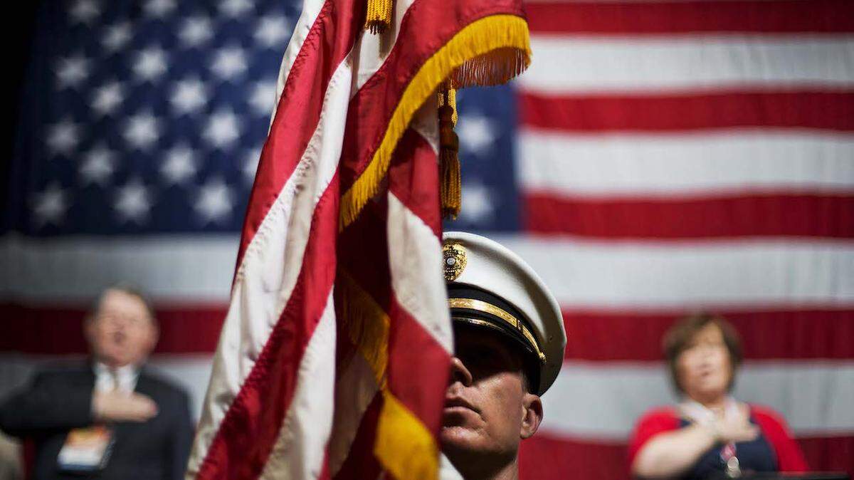 Officer Chris Armel, with the Honor Guard of the Athens-Clarke County Police Department, holds an American Flag during the "Pledge of Allegiance" at the convening of the Georgia Republican Convention Friday, May 15, 2015, in Athens, Ga. Georgia Republicans will hear from three White House hopefuls, New Jersey Gov. Chris Christie, Florida Sen. Marco Rubio and Texas Sen. Ted Cruz as the party gathers for its annual convention Friday. The appearances come as Georgia Republicans look to raise their profile in the 2016 nominating contest. (AP Photo/David Goldman)