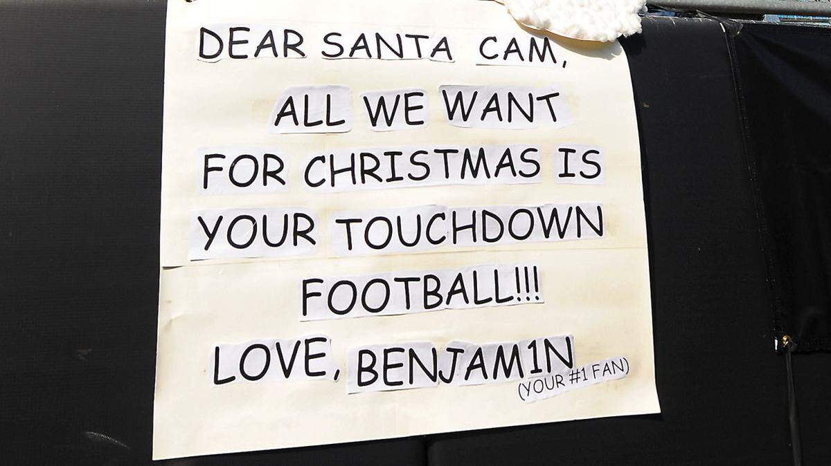 It's never too early to start planning for Christmas gifts as Carolina Panthers fan Randy Goins places a Cam Newton photo onto a sign prior to the game requesting a touchdown football. Goins along with his fiance Rachel Rankin and son Benjamin Rankin, 4 yrs. prepared for the team's game vs the Atlanta Falcons at Bank of America Stadium in Charlotte, NC on Sunday, November 16, 2014.