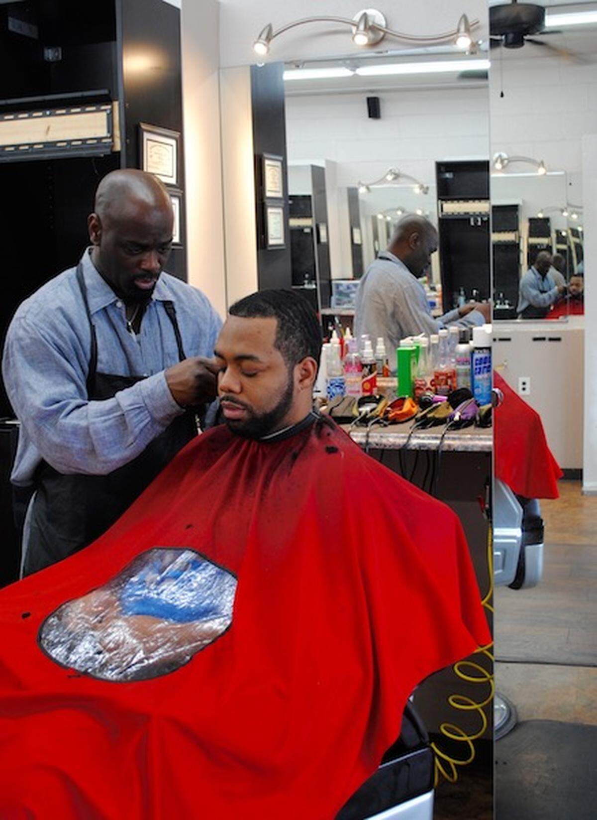 Kutty, 46, cuts the hair of Javaris, 30, at Premier Grooming Lounge.