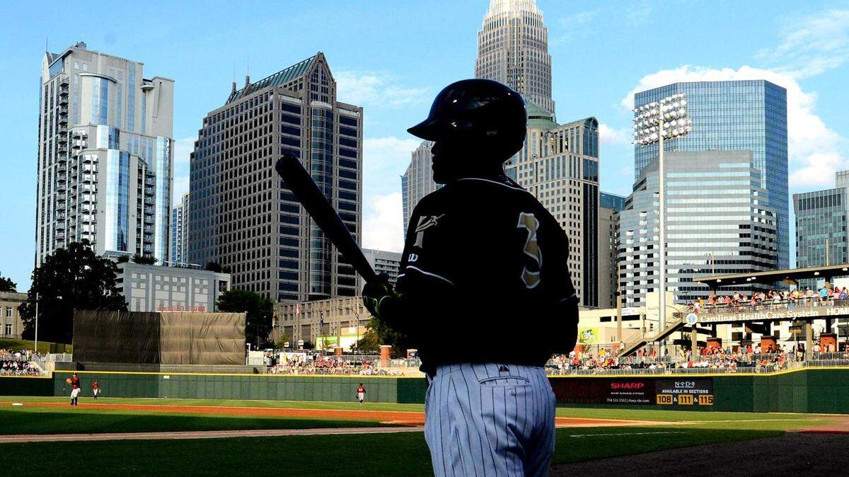 Charlotte Knights Micah Johnson (3) is partially silhouetted against the skyline of Charlotte, NC as he heads to the batters box to face Scranton/Wilkes-Barre Railriders pitcher Bryan Mitchell (15) on Thursday, July 17, 2014 at BB&amp;T BallPark in Charlotte, NC.