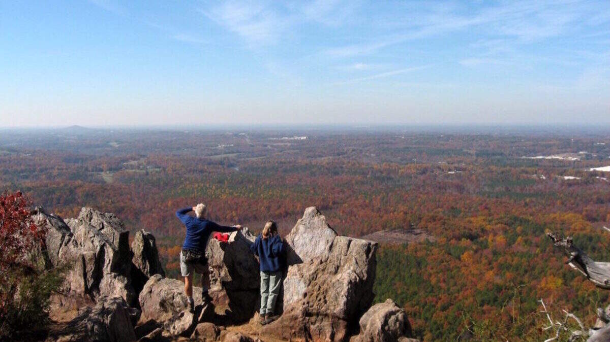 Hikers stand on the peak of Crowders Mountain overlooking the Piedmont.