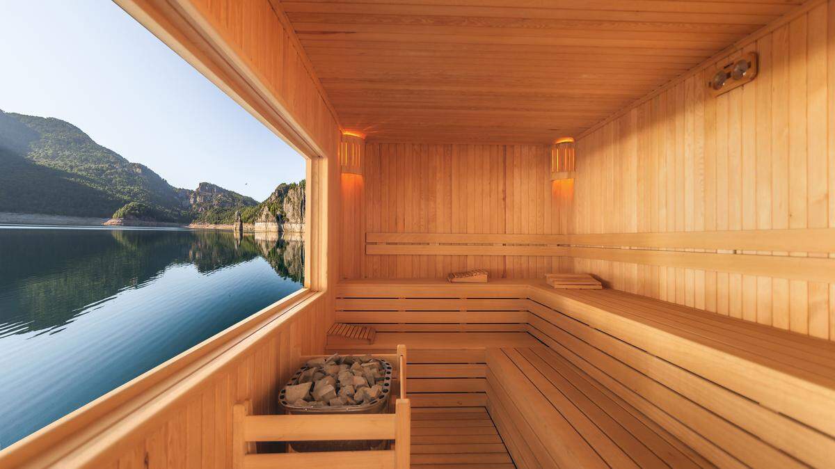 A wooden sauna with a view of a lake outside.