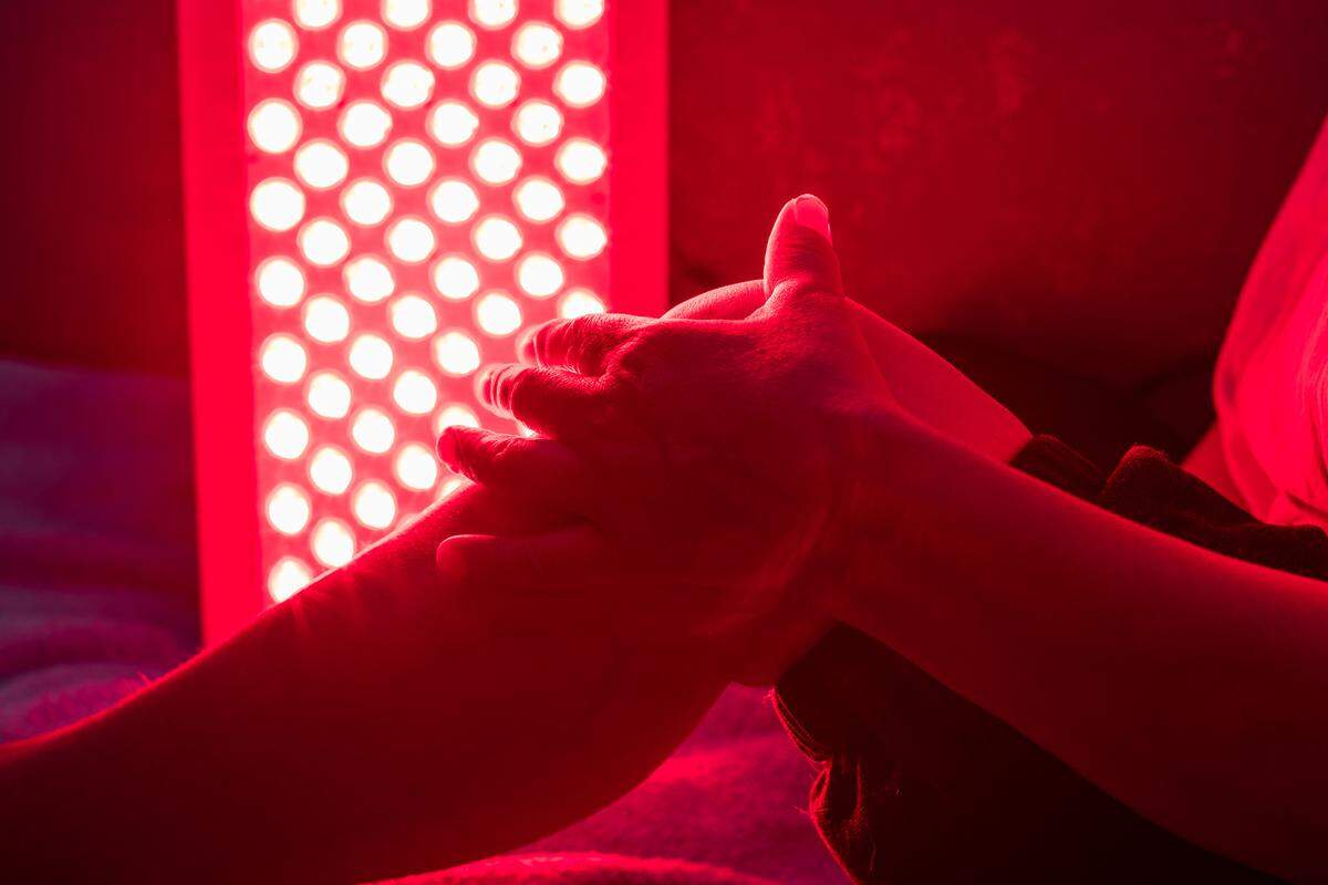 Closeup of someone treating their sore leg with a red light therapy panel.