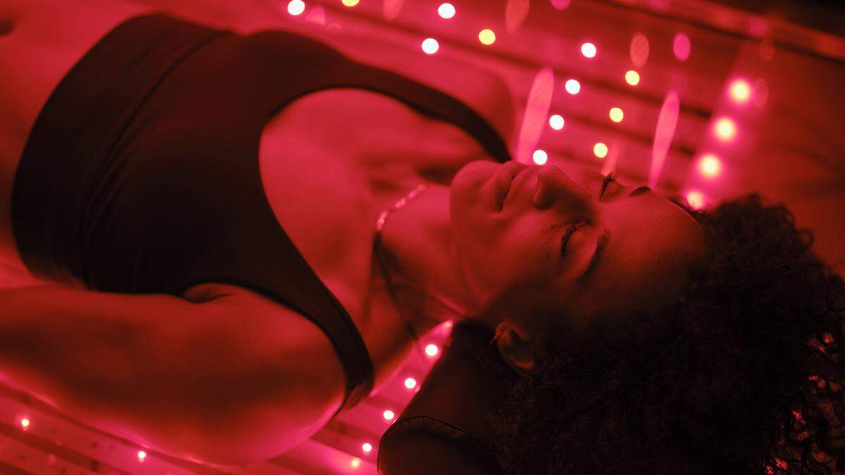 A woman on an LED light bed, receiving red light therapy.
