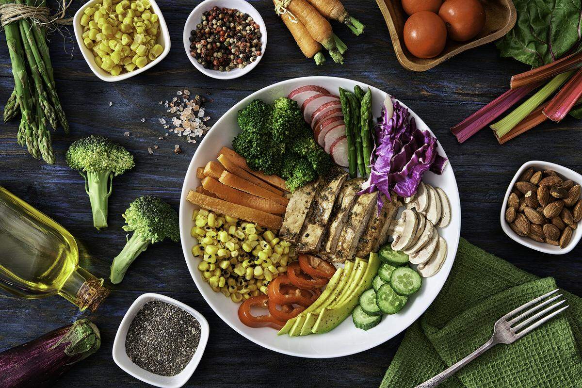 Healthy eating and diet concepts. Colorful spring salad on rustic white wood table. Included ingredients: Chicken, tomatoes, broccoli, lettuce, bell peppers, mushroom, carrots, radicchio, almonds.