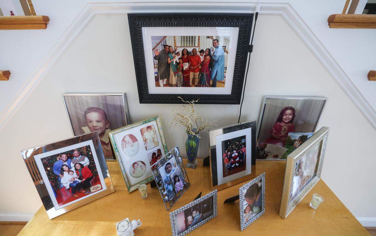 Family photos of Vasant and Champa Patel, their children, spouses and grandchildren fill a table in the entrance to their home in Charlotte on Monday, November 24, 2025. They are parents of actor and filmmaker Ravi Patel, and are well-known for their starring roles in the 2014 documentary film “Meet the Patels”.