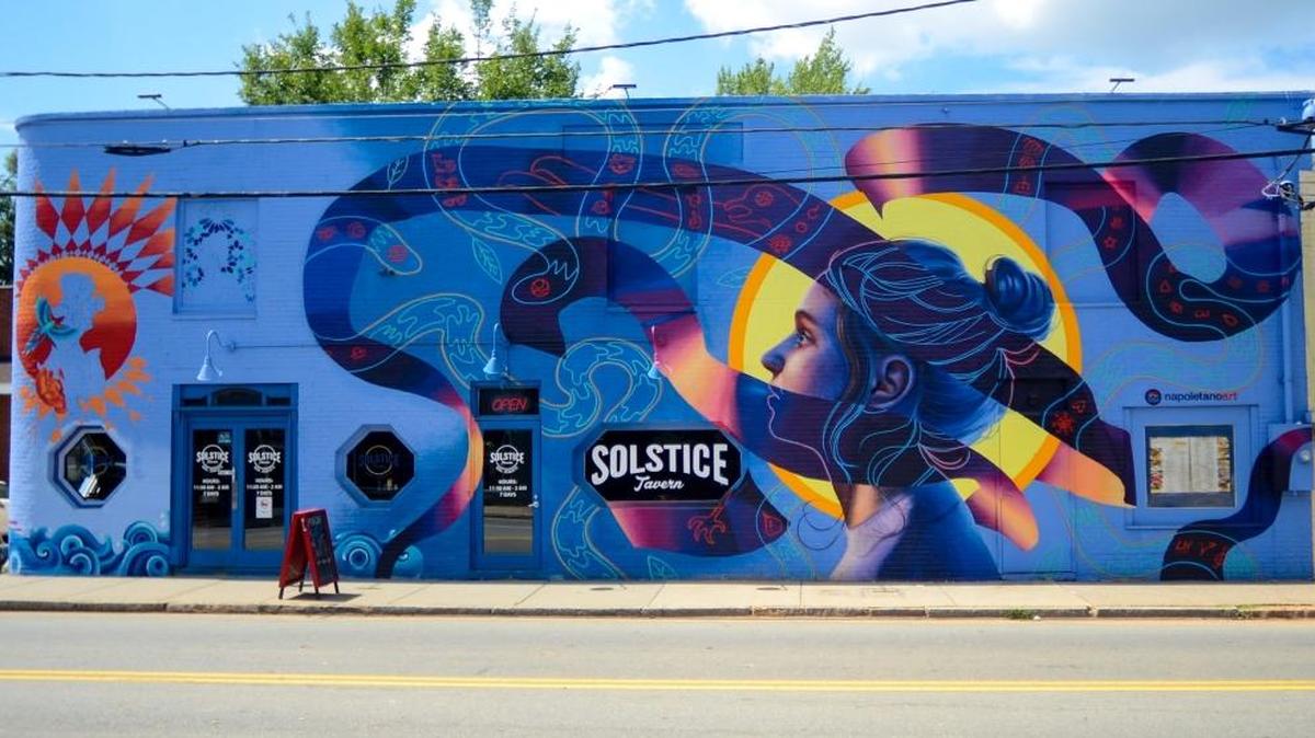 Nicholas Napoletano is a local artist and muralist who brought life to the bare walls of NoDa with his murals. One is painted on the side of Solstice Tavern and the other is a Stella Artois mural on the side of FU Custom Tattoos.