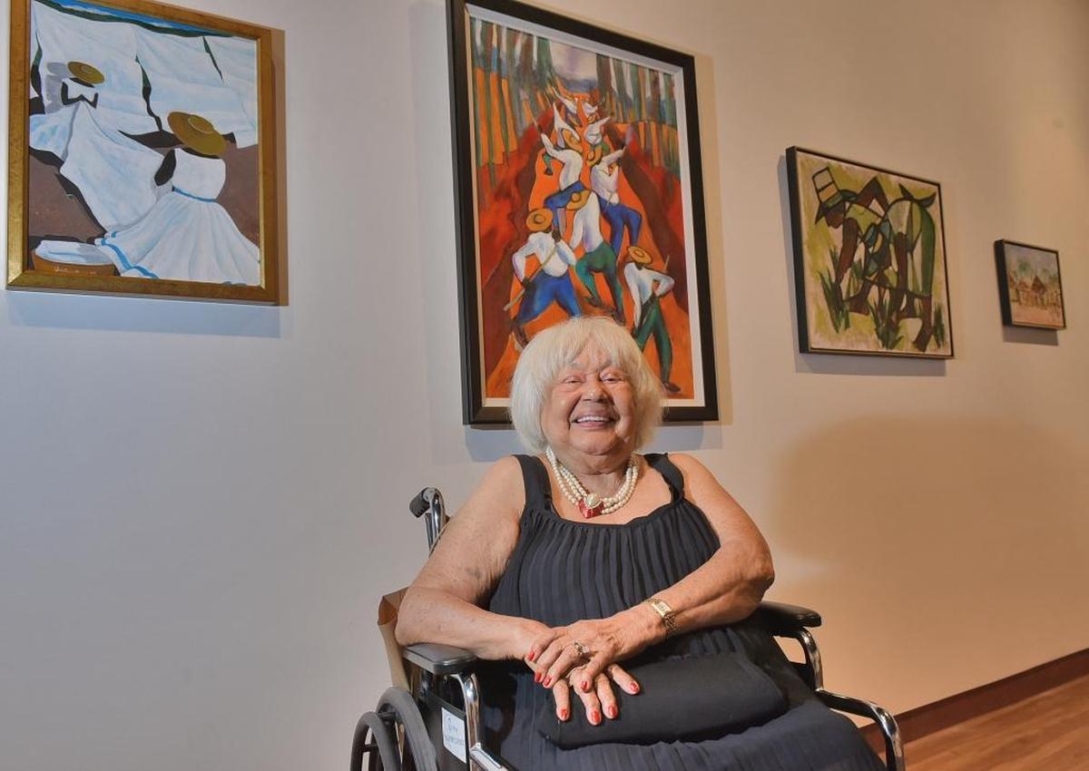 Collector Vivian Hewitt before some of the work in the “Instill & Inspire” exhibition: Jonathan Green’s “Folding Sheets,” and Ann Tanksley’s “Canal Builders,” both from 1989, and both in the Gantt’s permanent collection.