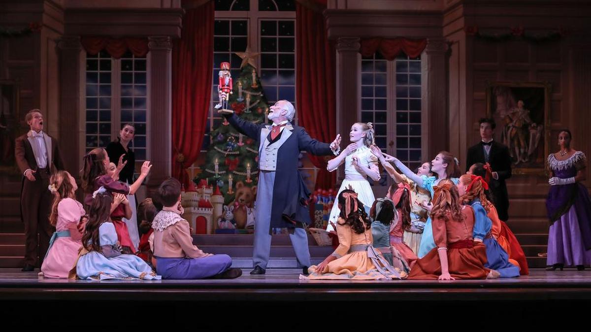 Mark Diamond holds the Nutcracker aloft, as Drosselmeyer, in Charlotte Ballet’s annual Nutcracker.