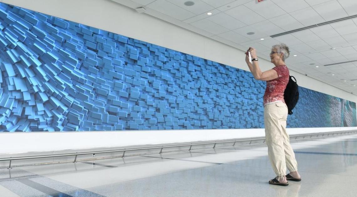 Despite hurrying to her flight home to Denver, Colorado Marilyn Oliver paused to make a photo of the newly revealed digital artwork by Refik Anadol. “I’ve never seen anything like this before”, Oliver said. Anadol has created an ever-changing piece of digital artwork that can be seen from both inside and outside the newly opened expansion of Concourse A at Charlotte Douglas International Airport. Passengers heading to their gates at the end of the expansion walk past the massive 139’ wide by 7’11” high art. The expansion of Concourse A happened opened for public use on Wednesday, July 18, 2018.