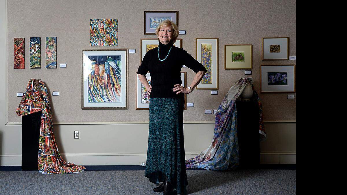 
Louise Napier with some of the artworks in her exhibit at Wingate called "Fabric to Fashion," at the Batte Center's C. Douglas Helms Gallery. The exhibit is a compilation of watercolor paintings, and children's clothing made of fabrics created by printing her original paintings on cloth. Napier is the chair of Wingate University's art department, and has been a professor for almost 50 years. She will retire this May. The exhibit runs through April 14. 
