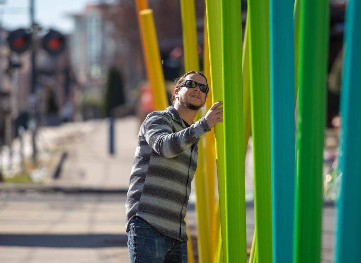 Local artist Ivan Toth Depena adjusts the angle of each pole as “The Color Forest” is installed on the Rail Trail.