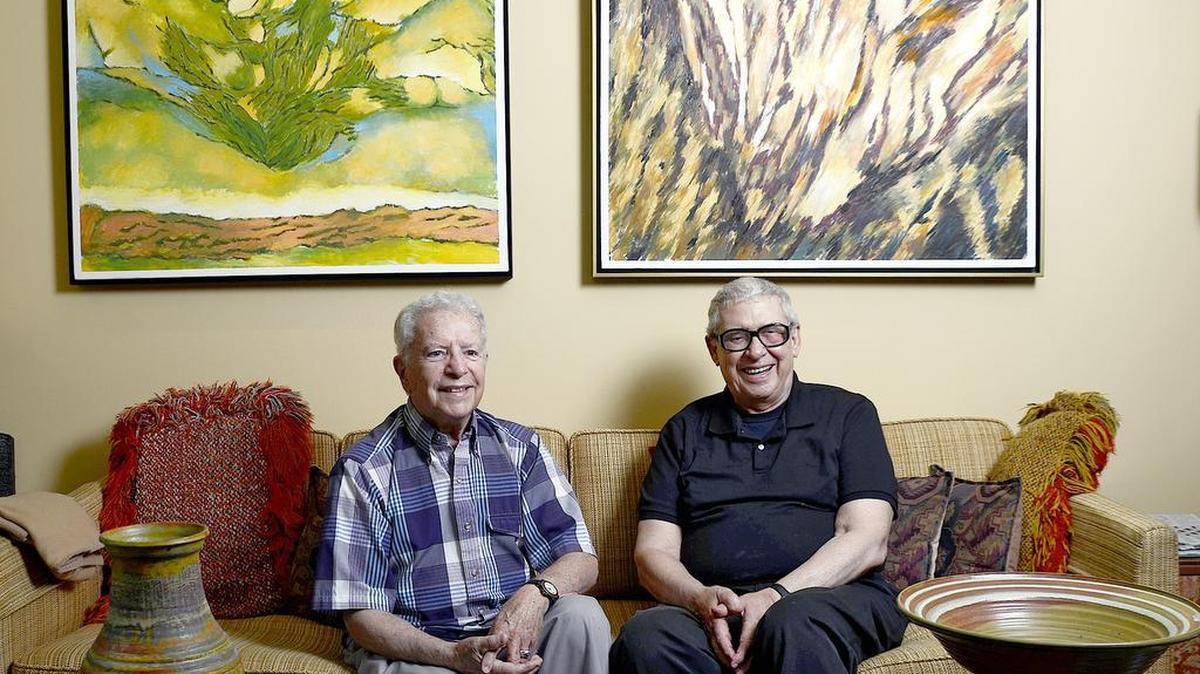 This 2012 Observer file photo shows Herb Cohen and José Fumero in their home, filled with their artwork. On the wall are Fumero’s paintings “Misty Mountains” and “Phoenix,” and on the table are pottery pieces by Cohen.