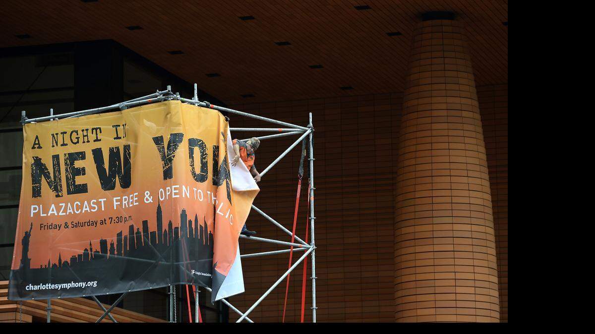 
Keith Evans, a stage hand with Local 322 helps hang a banner for the Charlotte Symphonies "A Night in New York," concert. The symphony is attempting to create a "tailgate" atmosphere for the next KnightSounds concert at Knight Theater. The Levine Avenue of the Arts will be closed off and the concert inside the theater will be projected for free to an audience outside.
