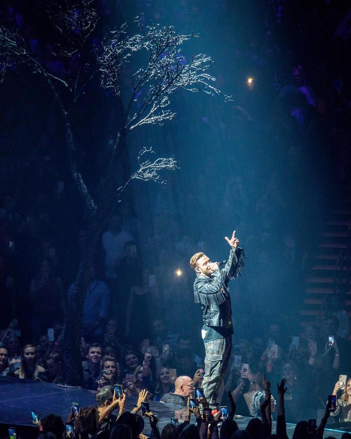 Justin Timberlake performs in the shadow of a big fake tree on stage at Spectrum Center.