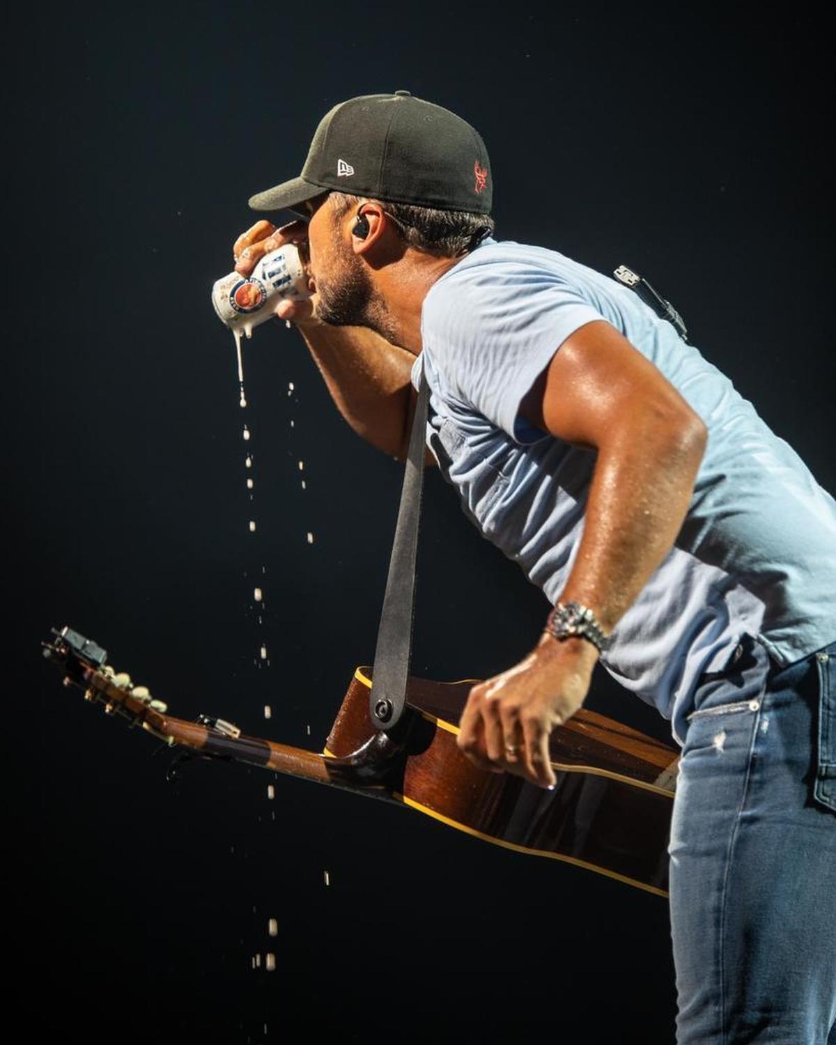 Luke Bryan quenches his thirst between songs at PNC Music Pavilion on Friday night.