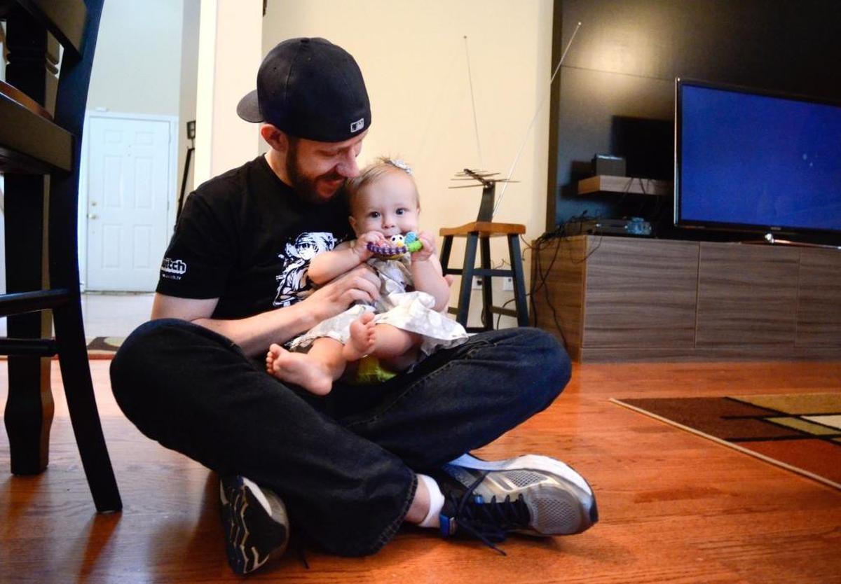 Tim MacRae plays with his daughter, Mia, before beginning work, playing Grand Theft Auto..