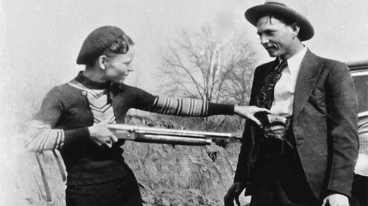 Bonnie Parker and Clyde Barrow, the most famous outlaw couple in U.S. history, posing together in front of car, 1933.