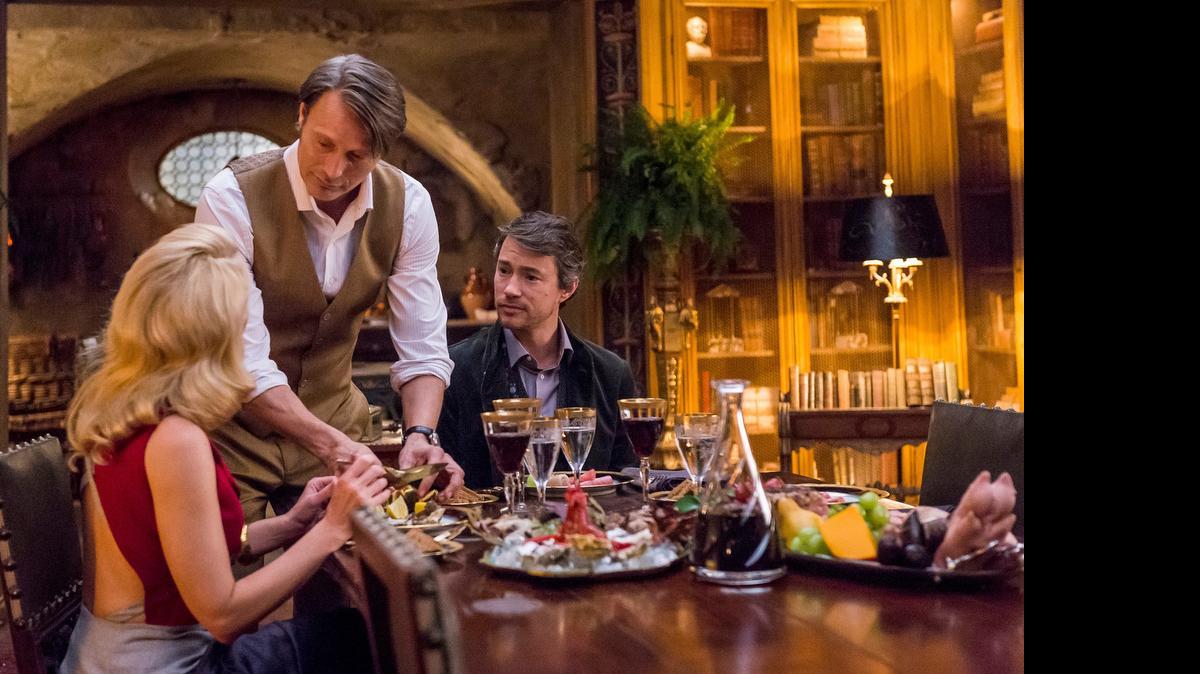 
(L-R): Gillian Anderson as Dr. Bedelia Du Maurier, Mads Mikkelsen as Dr. Hannibal Lecter and Tom Wisdom as Anthony Dimmond in “Hannibal.” 
